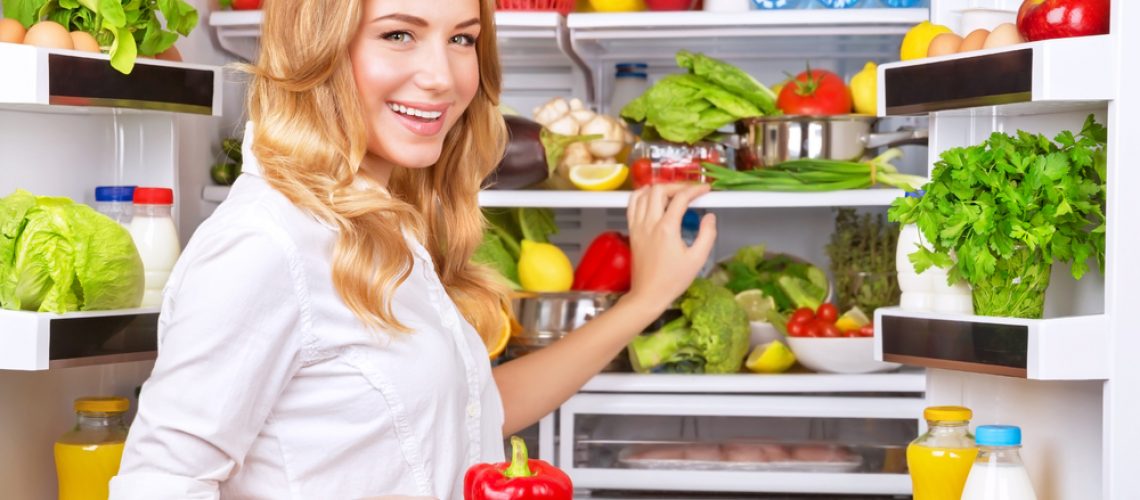 Housewife at the kitchen take red pepper from fridge full of fresh and tasty vegetables and fruits, organic food, healthy eating concept