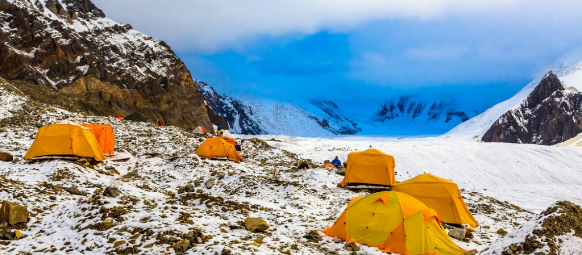 Base Camp of High Altitude Expedition Many Orange Tents Located on Side Rock Moraine of Glacier in Severe Snow and Ice Peaks Valley
